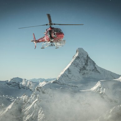 Helikopter in der Luft mit der Berglandschaft im Hintergrund | © Michael Portmann