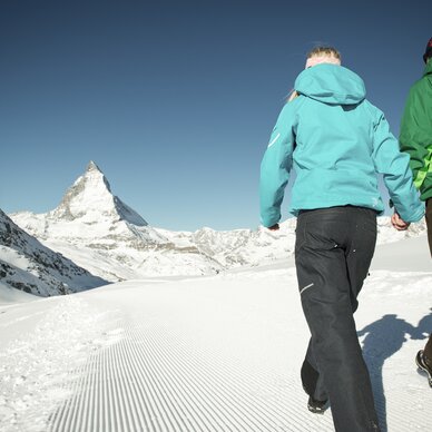 couple hiking in winter in front of Matterhorn