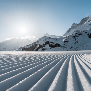 Groomers in the morning sun | © Basic Home Production Freshly prepared pistes sparkling in the morning sun in front of a mountain panorama | © Basic Home Production