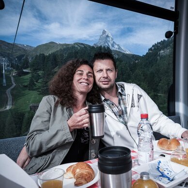 Couple enjoying breakfast in the gondola in front of the Matterhorn | © Marc Kronig