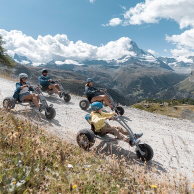 Mountaincart from Blauherd to Sunnegga | © BasicHomeProduction Four friends riding mountaincarts in front of the Matterhorn | © BasicHomeProduction