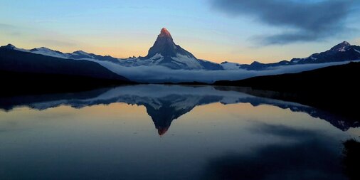 Colourful sunrise at lake Stellisee with the Matterhorn reflection on the water | © Zermatt Bergbahnen AG